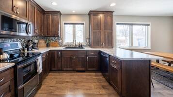 A modern kitchen with dark wood cabinets, stainless steel appliances, and a large island.