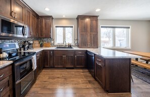 A modern kitchen with dark wood cabinets, stainless steel appliances, and a large island. - Dakota Haven: Family-Friendly, Clean, Sleeps 8 (Sioux Falls)