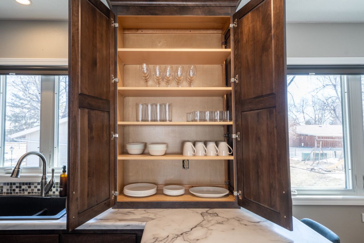 Un meuble de cuisine ouvert, avec des étagères contenant de la verrerie, des assiettes et des bols.