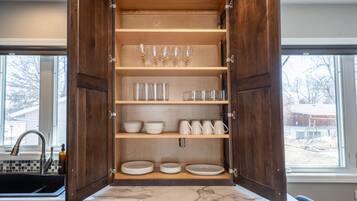 Un meuble de cuisine ouvert, avec des étagères contenant de la verrerie, des assiettes et des bols.