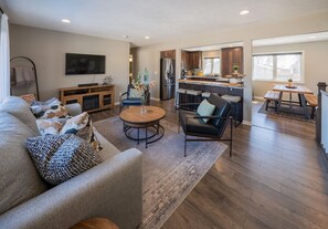 A spacious living room with a sofa, coffee table, and a TV mounted on the wall. - Dakota Haven: Family-Friendly, Clean, Sleeps 8 (Sioux Falls)