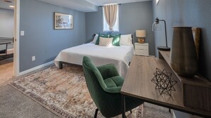 A bedroom with a bed, a desk, a chair, a lamp, and a decorative vase. - Dakota Haven: Family-Friendly, Clean, Sleeps 8 (Sioux Falls)