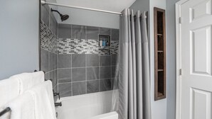 A bathroom with a bathtub, shower, and a towel rack. - Dakota Haven: Family-Friendly, Clean, Sleeps 8 (Sioux Falls)