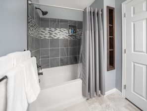 Ein Badezimmer mit einer Badewanne, einer Dusche und einem Handtuchhalter.