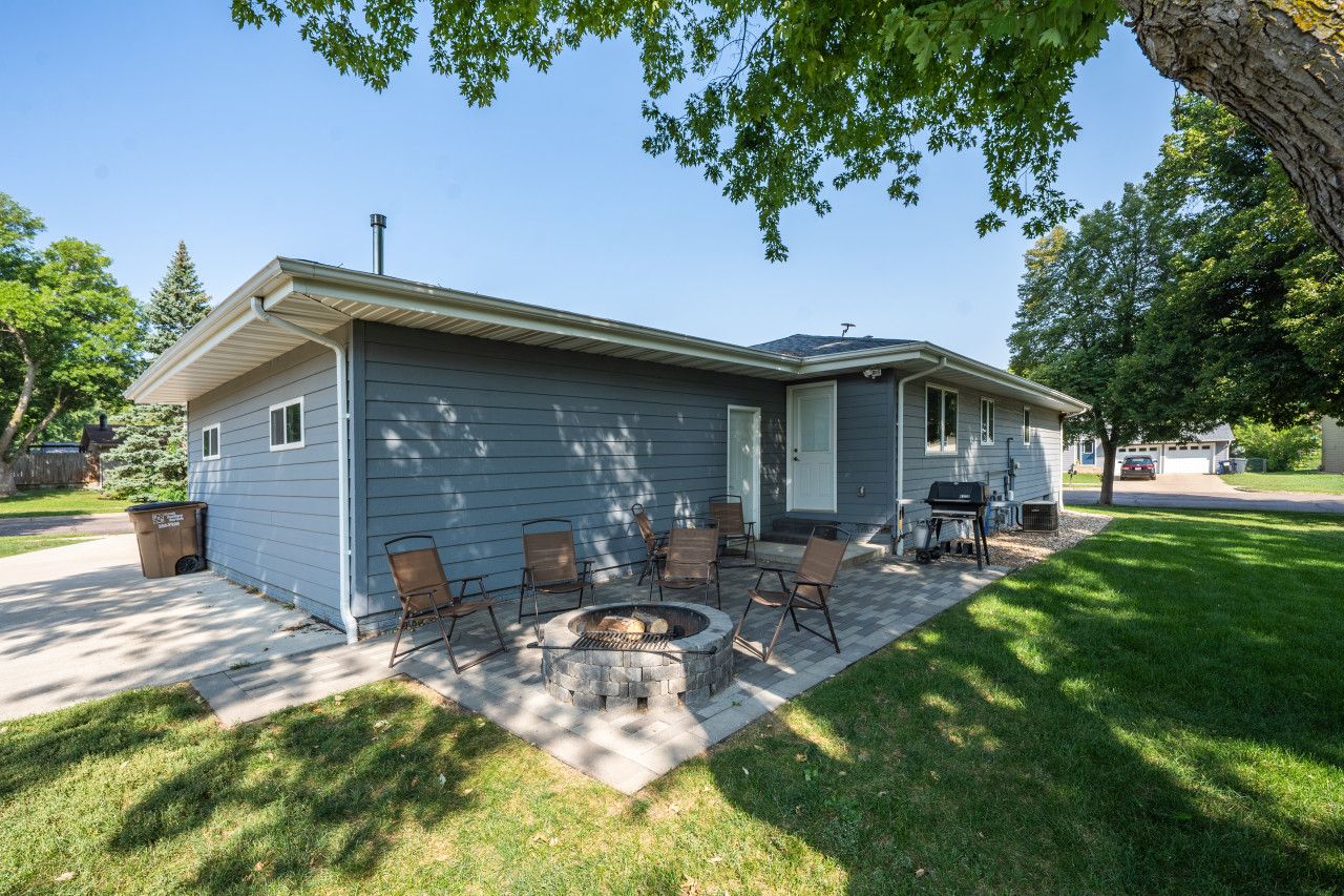 A residential house with a patio area featuring a fire pit and outdoor furniture.