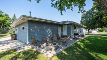 A residential house with a patio area featuring a fire pit and outdoor furniture.