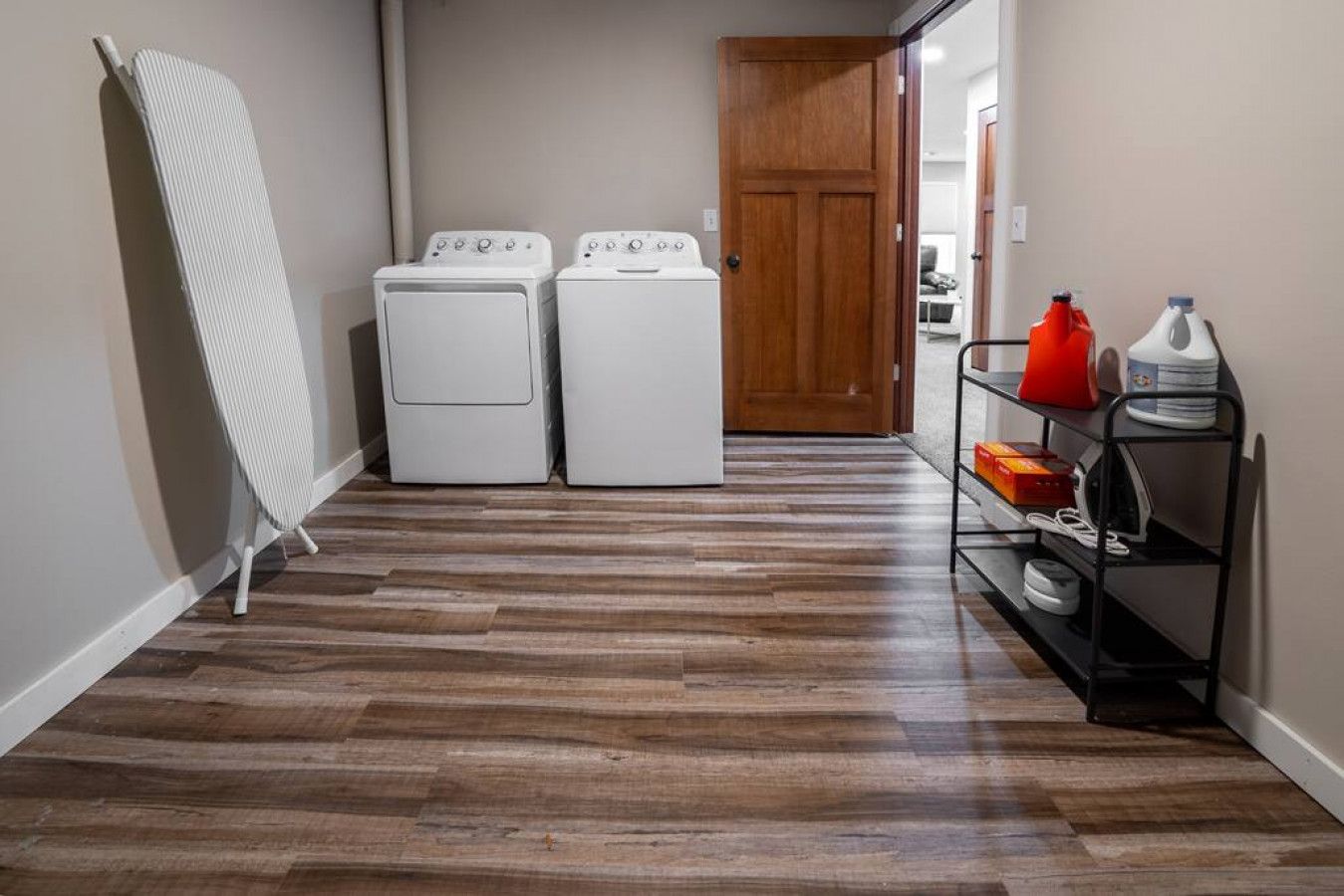A laundry room with two white washing machines and a drying rack.