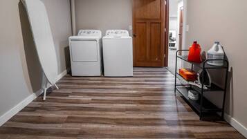A laundry room with two white washing machines and a drying rack.