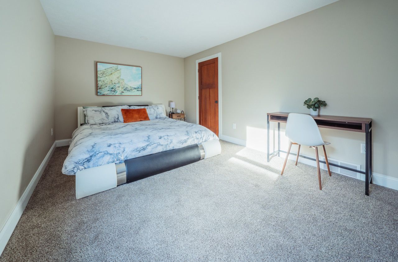 A bedroom with a bed, a desk, and a chair.