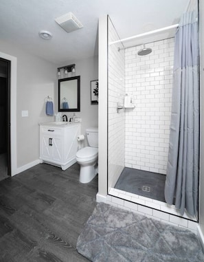 Ein Badezimmer mit begehbarer Dusche, Toilette, Waschbecken und Spiegel.