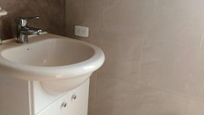 A bathroom with a white sink, cabinet, and a trash bin. - Hotel Rocio (Riobamba)