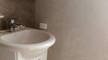 Un baño con un lavamanos blanco, un espejo y un cubo de basura.