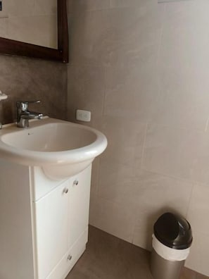 Ein Badezimmer mit einem weißen Waschbecken, einem Schrank und einer Mülleimer.