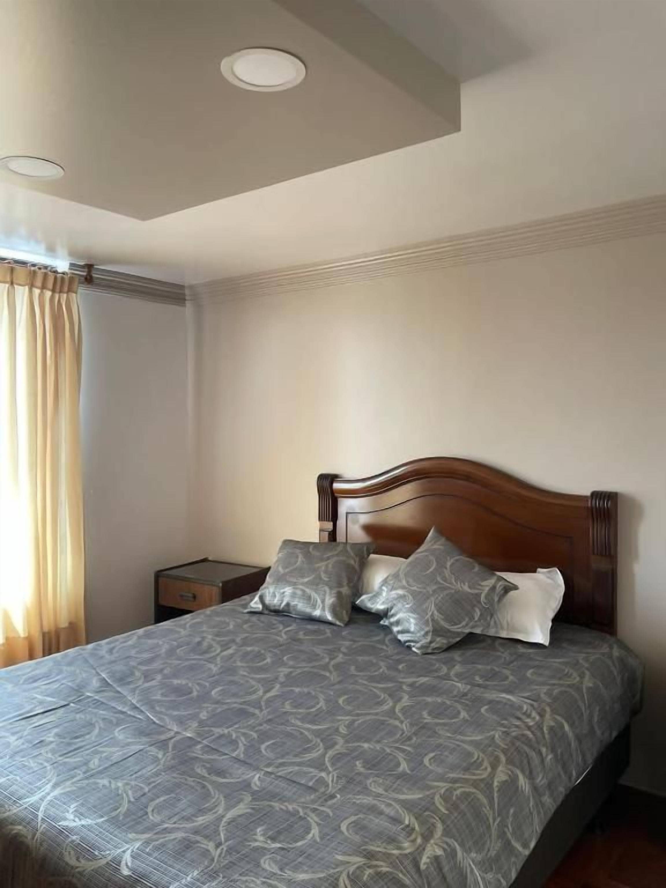 A bedroom with a bed, a nightstand, and a ceiling light.