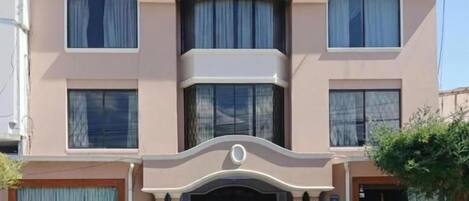 A hotel named 'HOTEL ROCIO' with a symmetrical facade, large windows, and a central entrance.