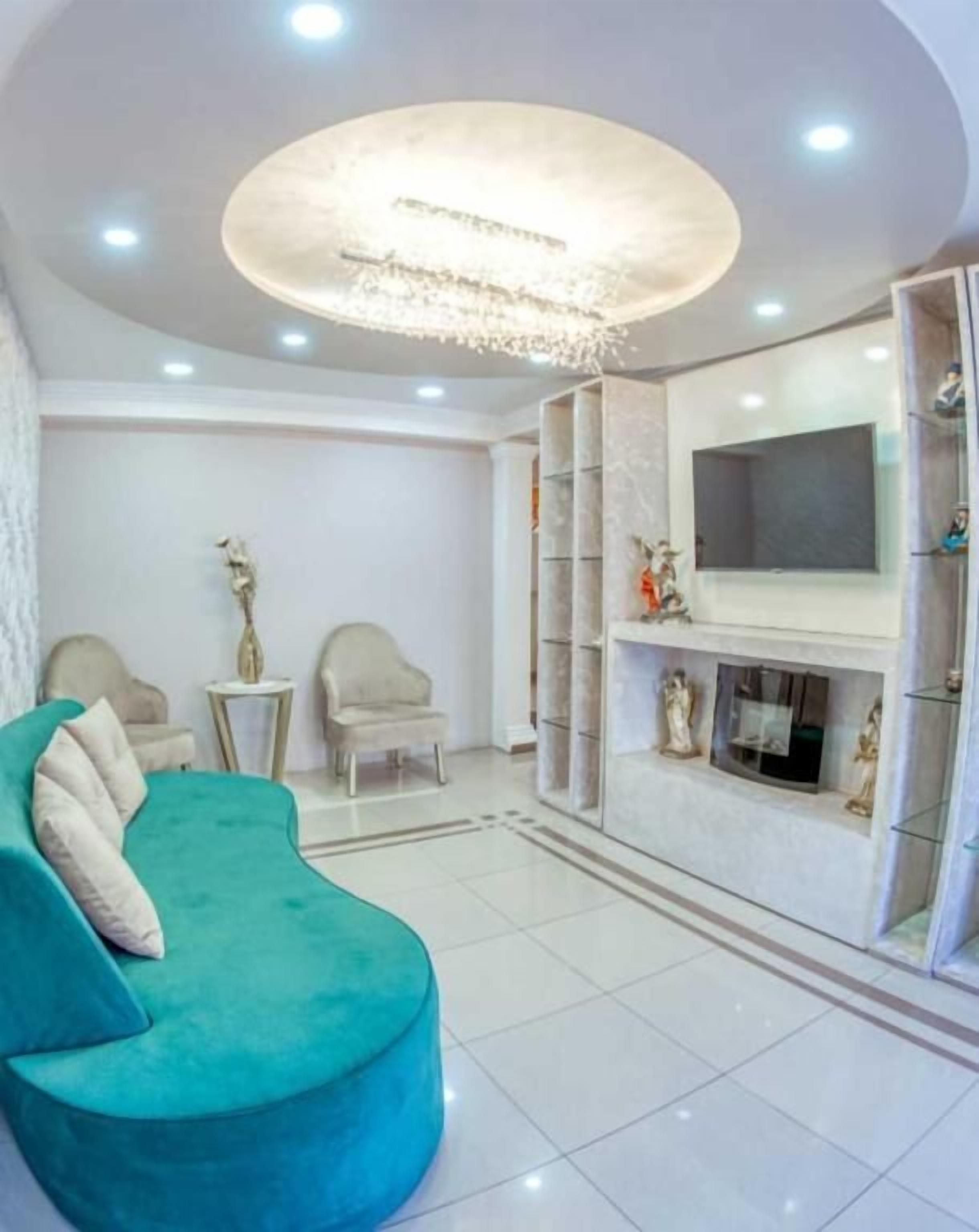 Una sala de estar moderna con un sofá color turquesa, una chimenea y un televisor montado en la pared.