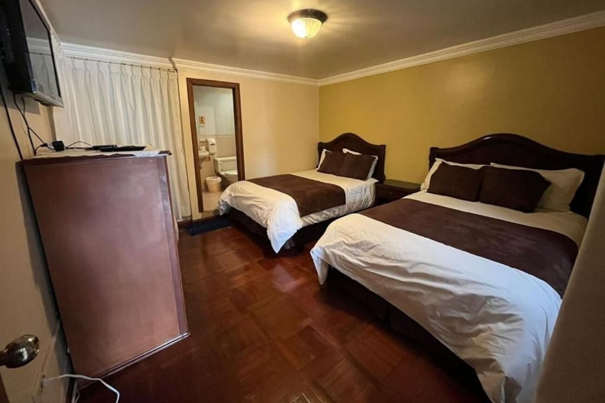 A hotel room with two beds, a television, and a door.