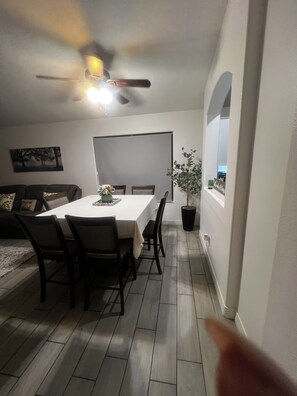 A dining area with a table, chairs, a ceiling fan, and a potted plant. - Our home comfortably sleeps up to 6 guests and features 2 bedrooms+bonus room. (Avondale)