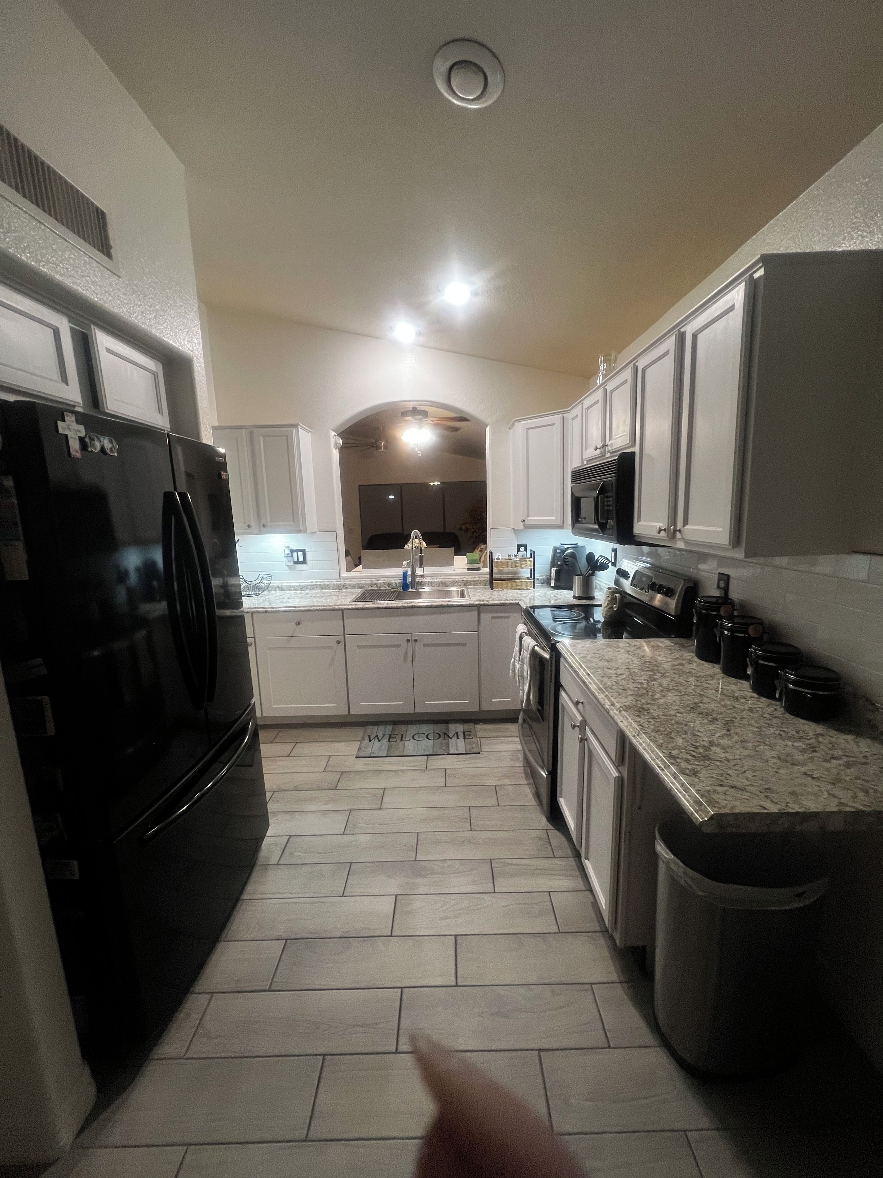 A kitchen with a refrigerator, microwave, sink, and cabinets.