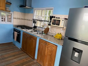 A kitchen with wooden cabinets, a stainless steel refrigerator, a microwave, and a sink. - Private Oasis Villa: Pool, BBQ Area & Lush Nature - Family Friendly (Provincia de Panamá Oeste, Corregimiento de Guayabito)
