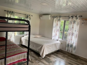 A room with a bunk bed, a single bed, a window with curtains, and an air conditioning unit. - Private Oasis Villa: Pool, BBQ Area & Lush Nature - Family Friendly (Provincia de Panamá Oeste, Corregimiento de Guayabito)
