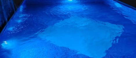 Une piscine dont la surface est texturée et qui comprend un espace central avec un jacuzzi.