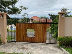 A gated entrance with a wooden gate and a metal gate, surrounded by greenery and a clear sky. - Private Oasis Villa: Pool, BBQ Area & Lush Nature - Family Friendly (Provincia de Panamá Oeste, Corregimiento de Guayabito)