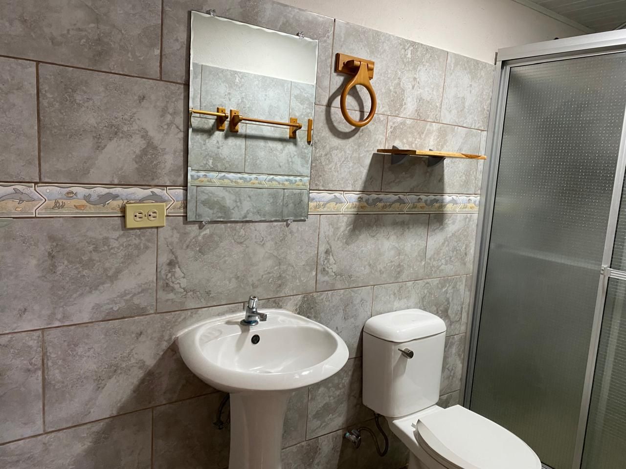 Ein Badezimmer mit Waschbecken, Toilette, Spiegel und Duschkabine.