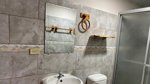 Een badkamer met wastafel, toilet, spiegel en douchecabine.