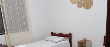 A room with two wooden beds, a small bedside table, and a decorative wall hanging.