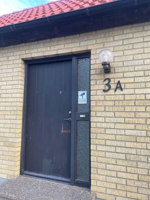A brick building with a black door and a security camera.
