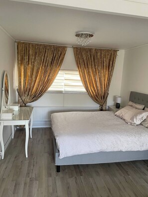 Une chambre à coucher avec un lit, une table de chevet, une lampe et des rideaux.