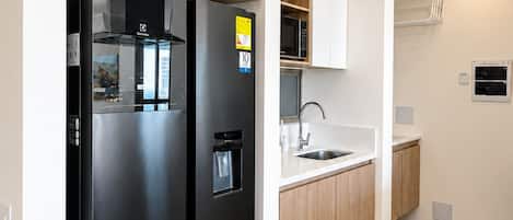 Una cocina moderna con un refrigerador negro, un microondas y armarios de madera.