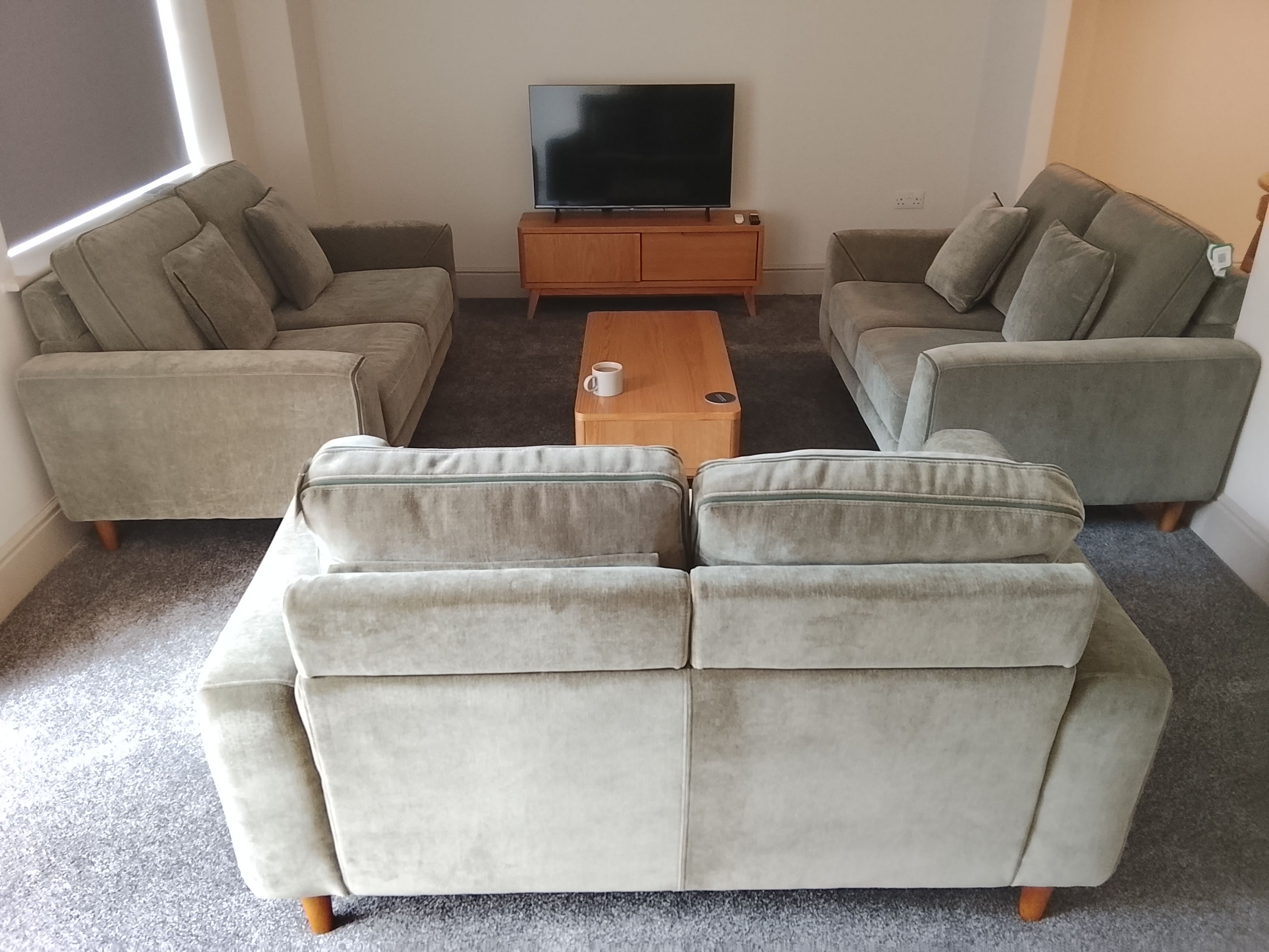 A living room with a sofa set, a coffee table, and a television on a wooden stand.