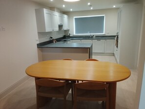 A modern kitchen with white cabinets, a large window, and a dining area with a wooden table and chairs. - Village House with open countyside views close by the bustling 'Norton Dog ' pub (Norton)