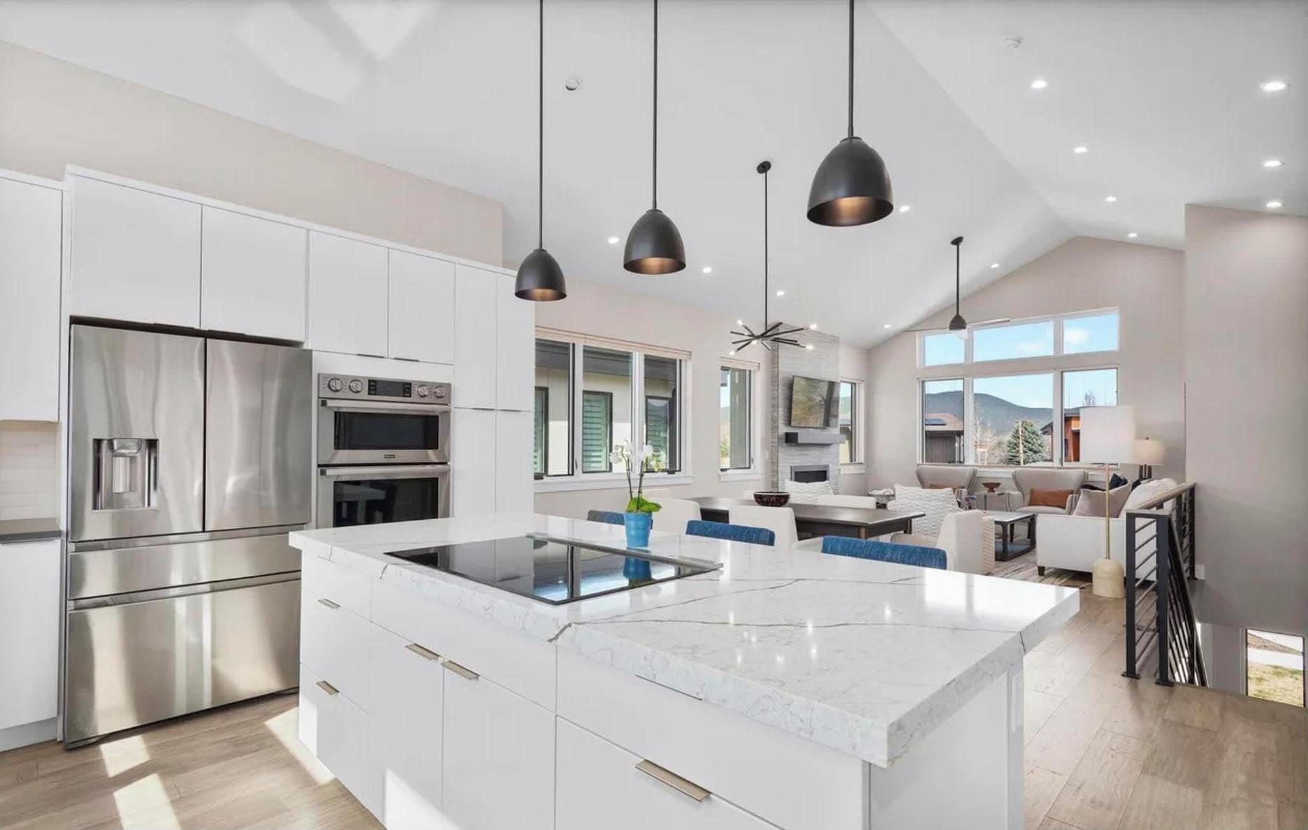 A modern kitchen with a large island, built-in appliances, and pendant lighting.