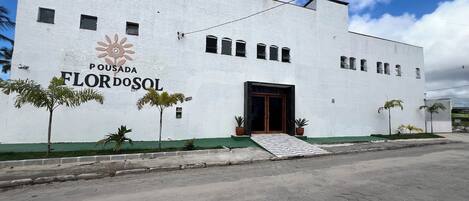 A white building with the sign 'Pousada Flor do Sol' and a staircase leading to the entrance.