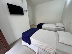 A hotel room with two beds, a TV mounted on the wall, and a small bedside table.