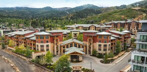 A multi-story hotel with a central building, surrounded by other structures, set against a mountainous backdrop. - Hilton Sunrise Lodge 2BR ski-in/ski-out condo in Canyons Village, Park City (Park City)