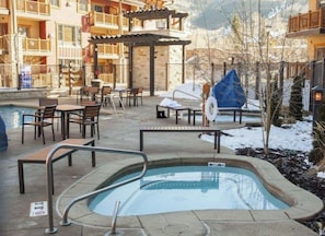 A pool area with lounge chairs and a hot tub, surrounded by a building with balconies. - Hilton Sunrise Lodge 2BR ski-in/ski-out condo in Canyons Village, Park City (Park City)