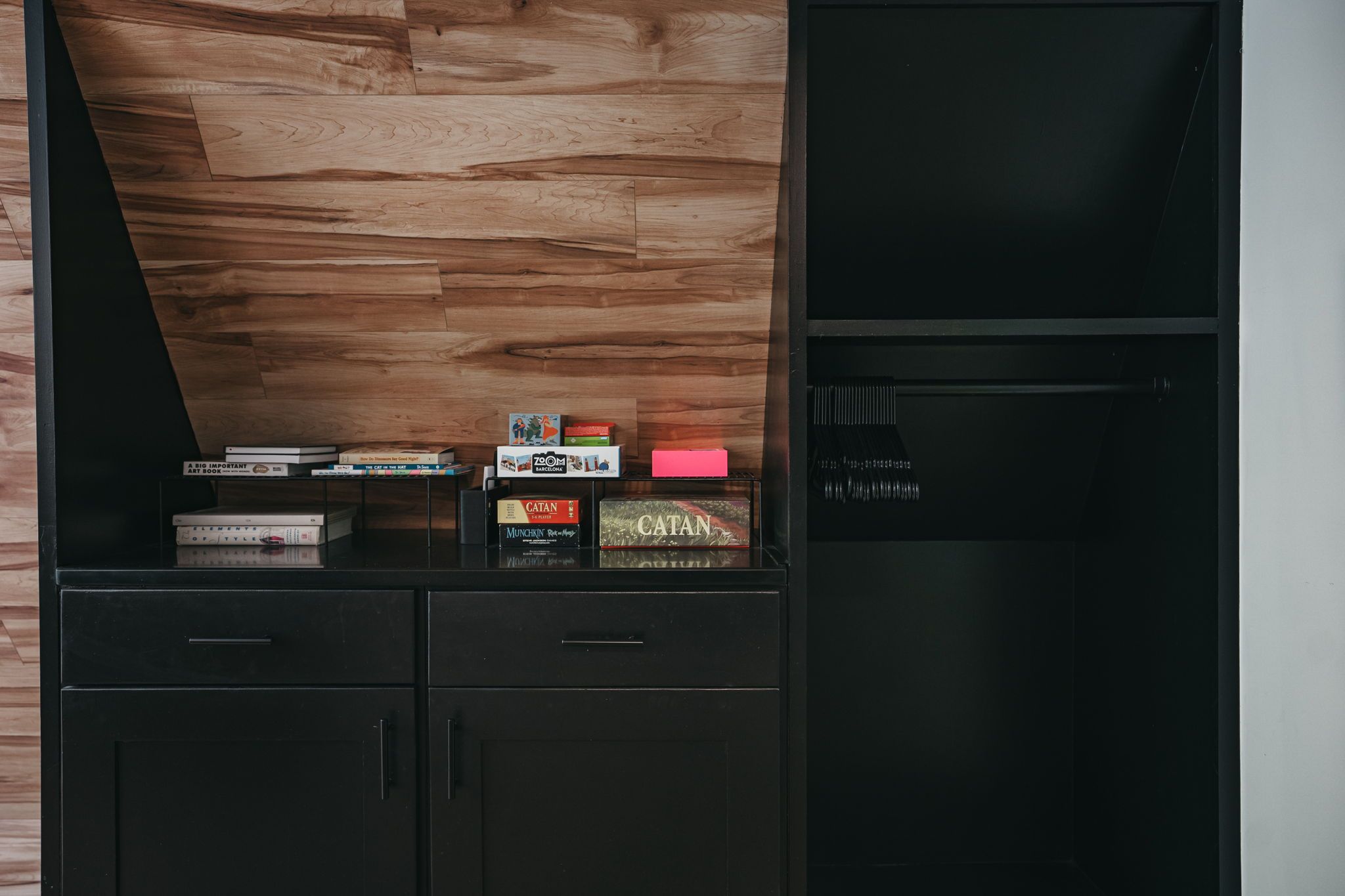 A wooden wall with a shelf holding books and board games.