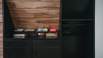 A wooden wall with a shelf holding books and board games.