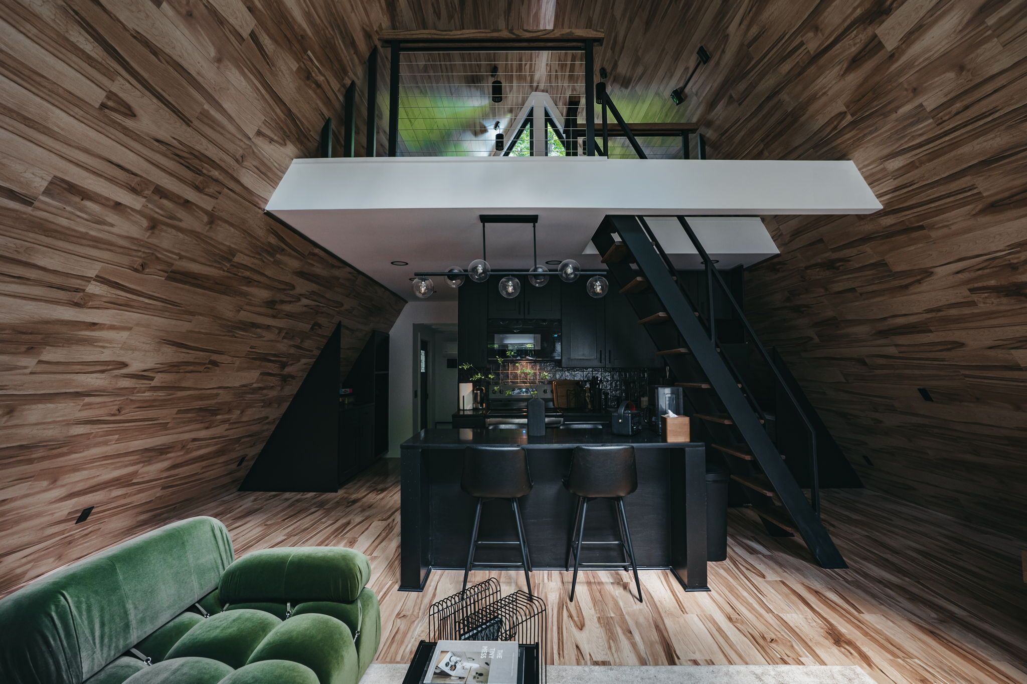 A modern loft-style interior with a kitchen area, a dining space, and a staircase.