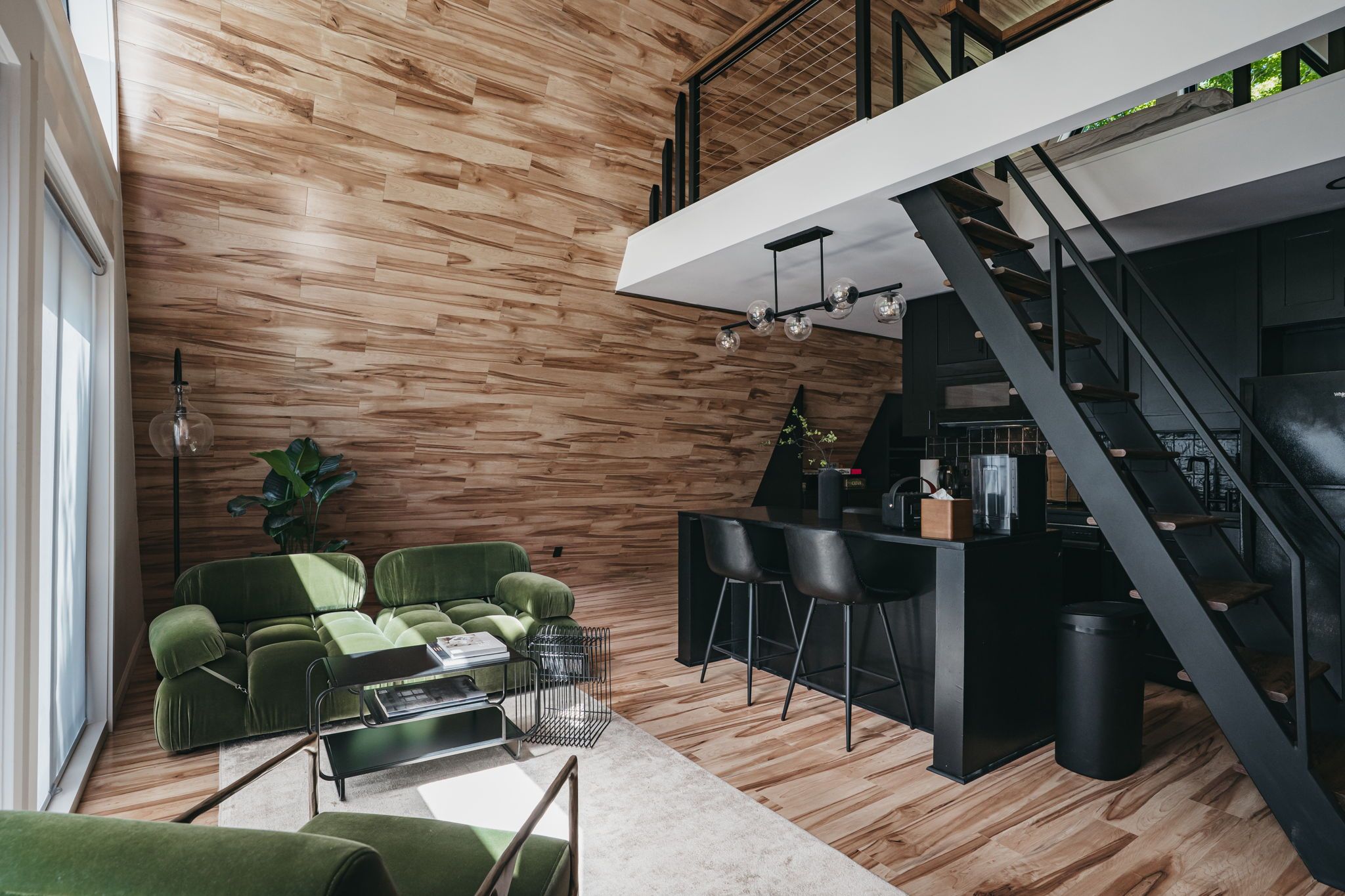A modern interior with a wooden wall, a staircase, a dining area, and a seating arrangement.
