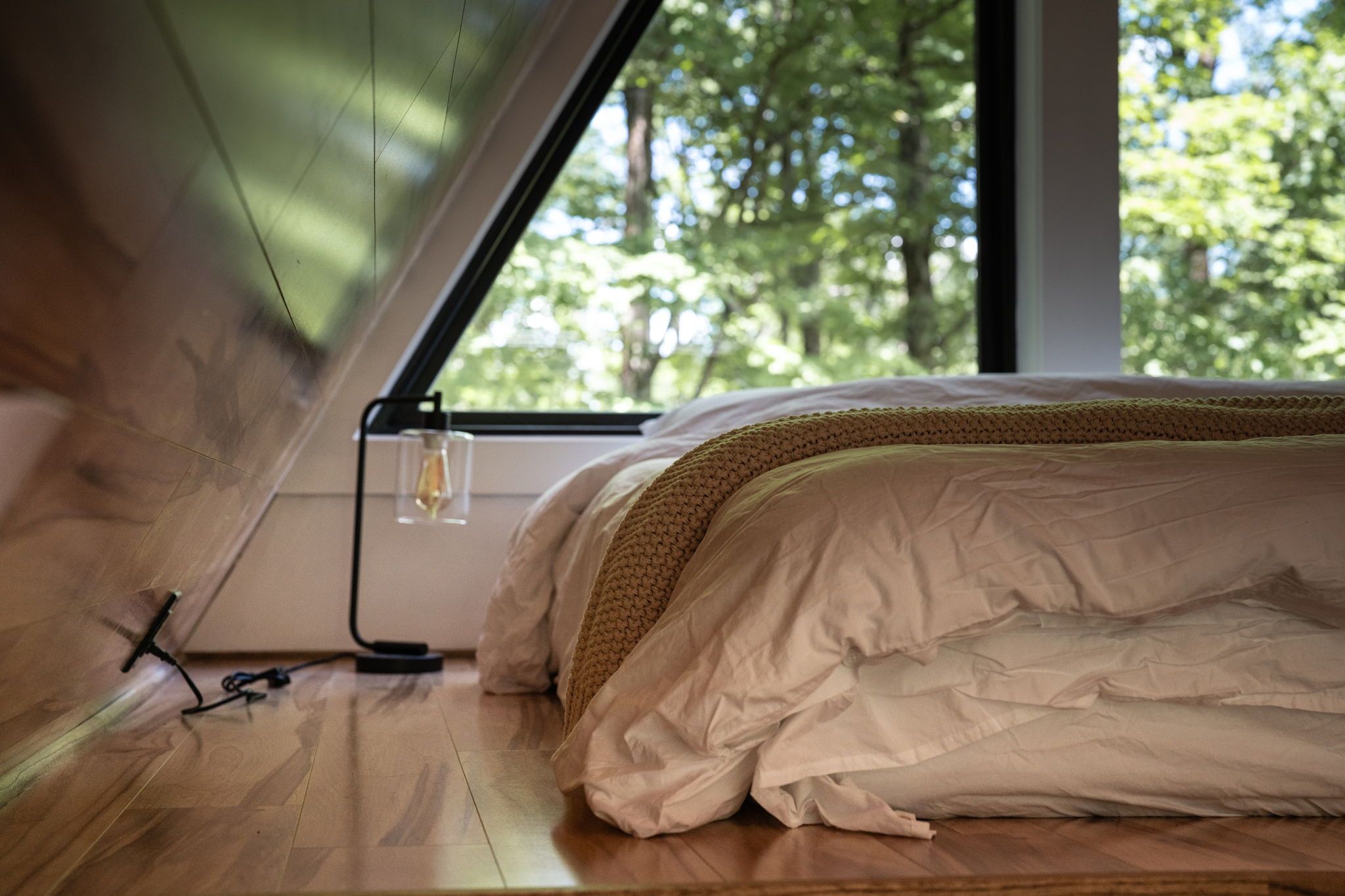 A bedroom with a bed, a window, and a power outlet on the floor.