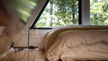 A bedroom with a bed, a window, and a power outlet on the floor.