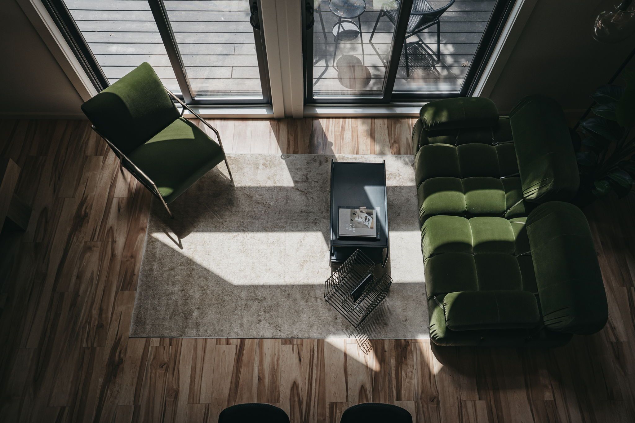 A modern living room with a green sofa, a matching armchair, and a coffee table.