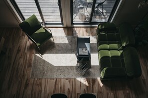 Een moderne woonkamer met een groene bank, een bijpassende fauteuil en een salontafel.