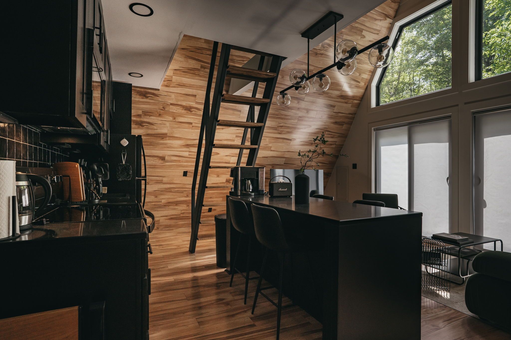 Une cuisine moderne avec un plancher en bois, un îlot central et une échelle intégrée.