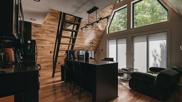 Eine moderne Küche mit Holzboden, einer zentralen Kochinsel und einem Essbereich mit einer schwarzen Sofaecke.